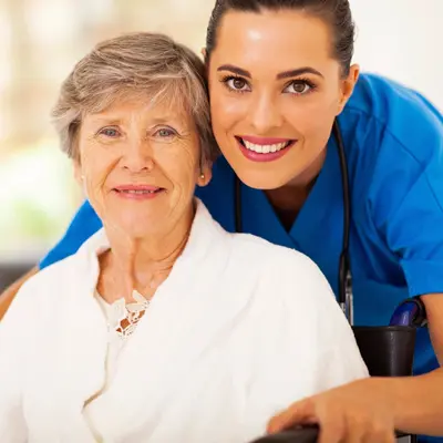 A nurse and an elderly woman smiling for the camera.
