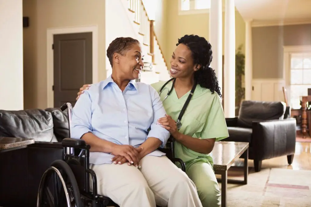 a nurse and a person in a wheelchair smiling at each other